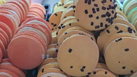 Assorted macaron cookies in orange and yellow colors with chocolate sprinkles Stock Footage 297012598