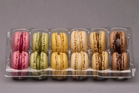 Assorted macarons in plastic box on gray background Foto stock
