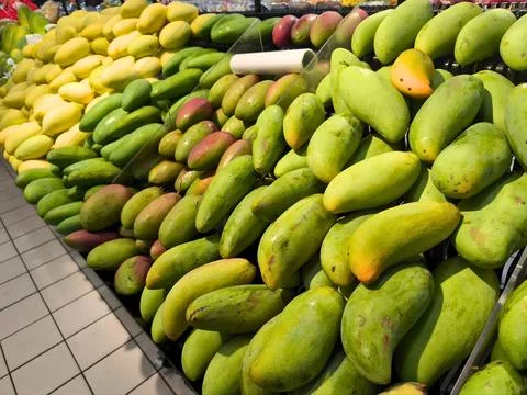 Assorted mango varieties in market display with yellow, green, and reddish hues Stock Photos