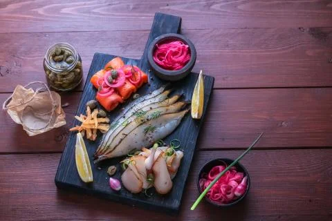 Assorted marinated fish on dark cutting board, copy space Stock Photos