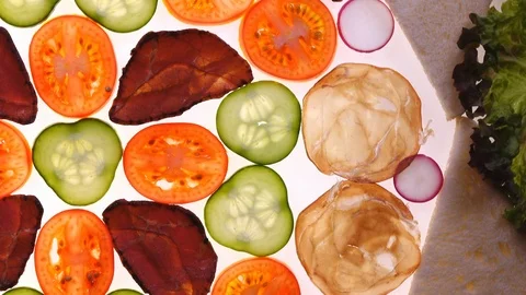 Assorted meat with fresh sliced vegetables and bread rotating on white Vídeo Stock 90219049