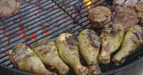 Assorted Meats Cooking and Being Moved on a Hot Charcoal BBQ Grill Stock Footage 321424971