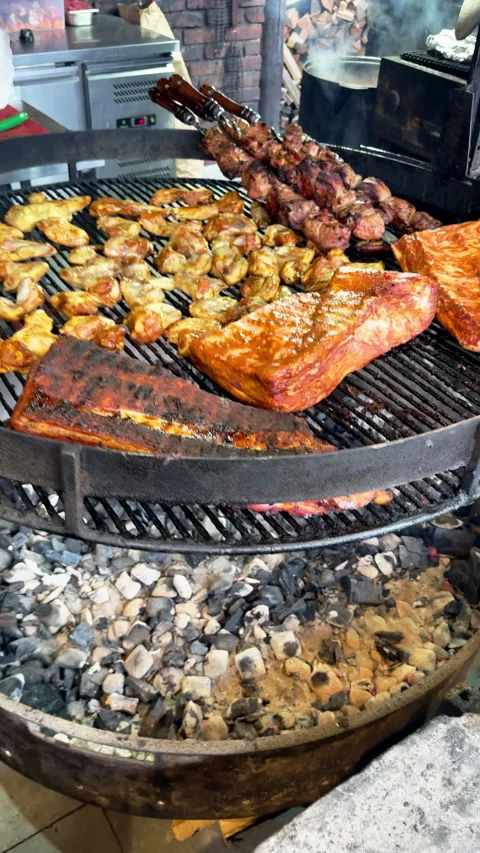 Assorted meats cooking on a large charcoal barbecue grill Video stock 324598094