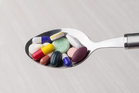 Assorted medication pills in a spoon. Supplements and ultra-processed food Stock Photos