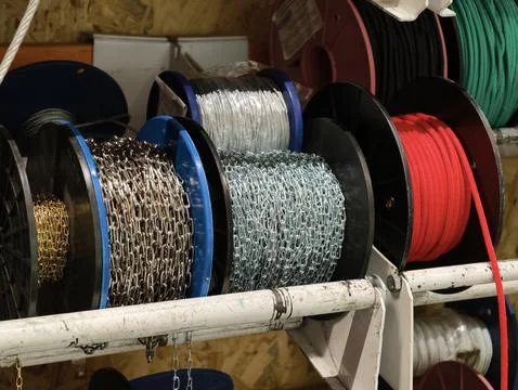Assorted metal chains and rope bundles coiled on reels in a supermarket har.. Stock Photos