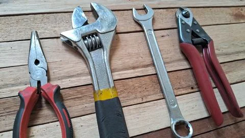 Assorted metal hand tools arranged on a rustic wooden table surface Stock Photos