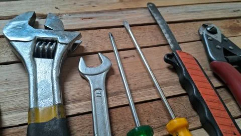 Assorted metal hand tools arranged neatly on a rustic wooden surface Stock Photos