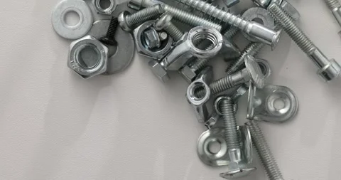 Assorted Metal Nuts, Bolts, and Washers on White Surface Stock Footage 293370641