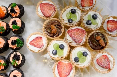 Assorted mini desserts on a platter, featuring fruit tarts and chocolate trea Stock Photos