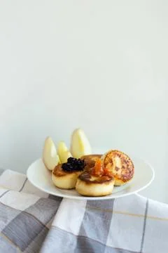 Assorted mini pancakes with syrup and fruit on white plate Stock Photos