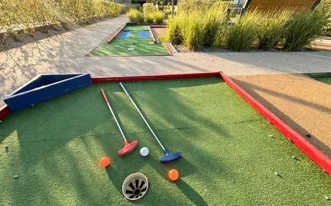 Assorted miniature golf putters and balls askew on synthetic grass. Stockfoto's