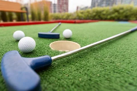 Assorted miniature golf putters and balls askew on synthetic grass. Stockfoto's