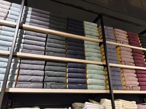 Assorted multicolored towels placed neatly on spacious shelves in home supp.. Stock Photos