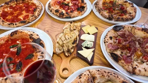 Assorted Neapolitan Pizzas and Red Wine on a Restaurant Table Stock Footage 338319171