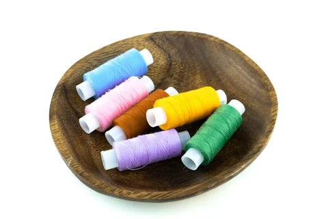 Assorted needlework threads folded in a wooden bowl on an isolated background Stock Photos