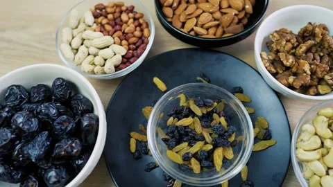Assorted nuts and dried fruits in bowls on a wooden table Stock Footage 320727502