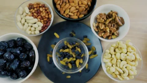 Assorted nuts and dried fruits in bowls on a wooden table Stock Footage 320727518