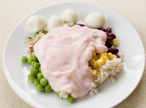 Assorted nuts and quail eggs topped with strawberry yogurt white dish Stock Photos