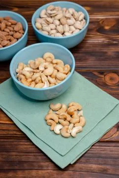 Assorted nuts in dishes on wooden table. Pistachios, cashews, almonds Foto stock
