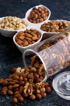 Assorted nuts in a dried fruit store on a gray textured background Stock Photos