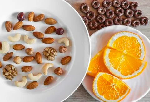 Assorted Nuts, Orange Slices On White Plates, Crunchy Whole Grain Cereals Rou Stock Photos