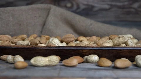 Assorted nuts-peanuts and almonds in wooden plate Stock Footage 124528446