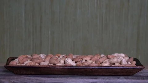 Assorted nuts-peanuts and almonds in wooden plate on an old wooden background Video stock 124555522