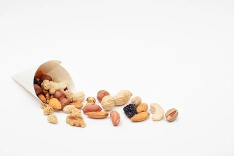 Assorted  Nuts  spill out of a paper cone on white background Stock Photos
