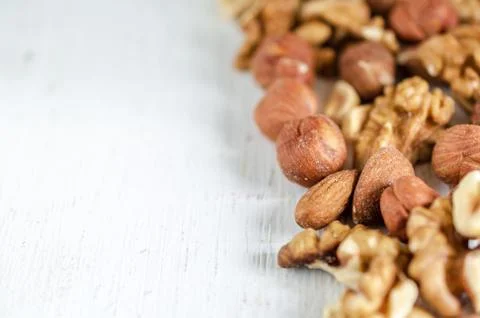 Assorted of nuts on white wooden table. Peanut, hazelnuts, walnuts, almonds. Stock Photos
