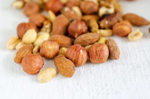 Assorted of nuts on white wooden table. Peanut, hazelnuts, walnuts, almonds. Stock Photos