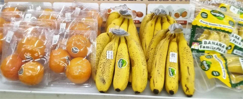 Assorted packaged fruit including bright oranges and yellow bananas  Stock Photos