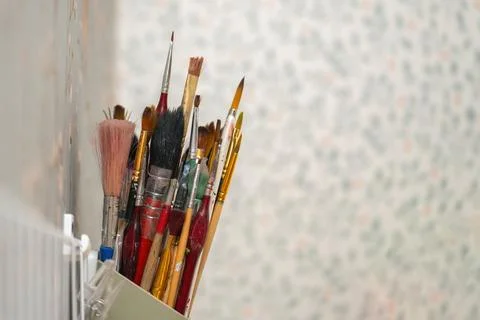 Assorted paintbrushes for artwork stored in a wall-mounted holder, showcasing Stock Photos