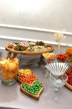 Assorted party snacks, chips, cheese, meat, and vegetables arranged on a serv Stock Photos