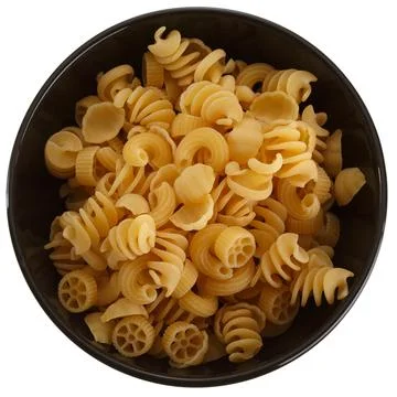 Assorted pasta in black round clay bowl isolated on white background, top vie Stock Photos