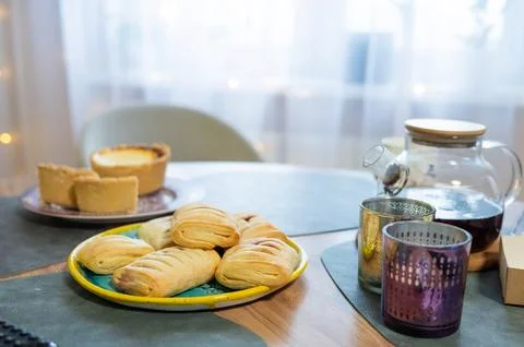 Assorted pastries and tea on table in cozy kitchen setting Stock Photos