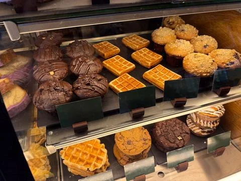 Assorted pastries and waffles displayed inside bakery showcase. Food select.. 스톡 사진