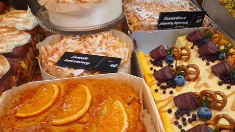 Assorted pastries displayed in a bakery showcase with cream-topped desserts Stock Footage 337732591