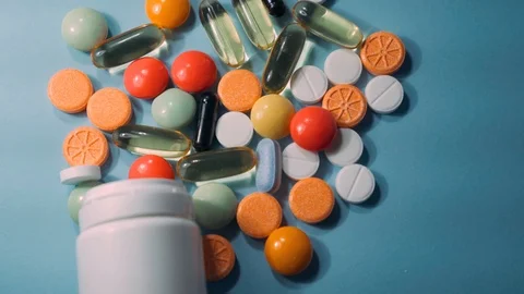 Assorted pharmaceutical medicine pills, tablets and capsules and bottle on blue Stock Footage 101016204