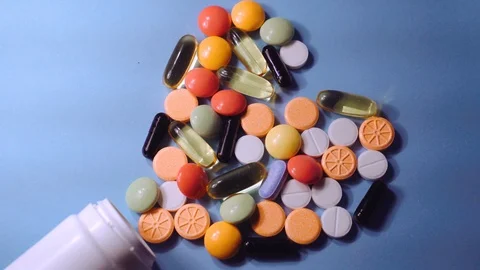 Assorted pharmaceutical medicine pills, tablets and capsules and bottle on blue Stock Footage 101016412