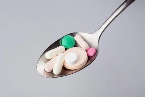 Assorted pharmaceutical medicine tablets, tablets and capsules on a metal spoon. Foto stock