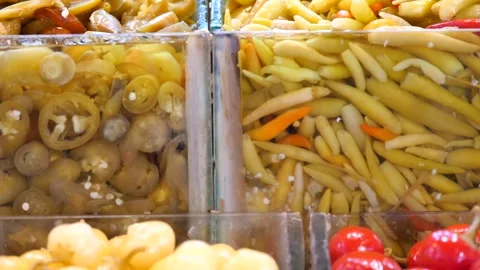 Assorted pickled chili peppers displayed in clear containers with brine, cl.. Vídeo Stock 333152681