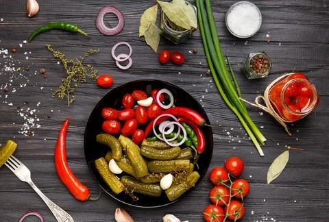 Assorted pickled vegetables in a black plate on a dark background top view. Stock Photos