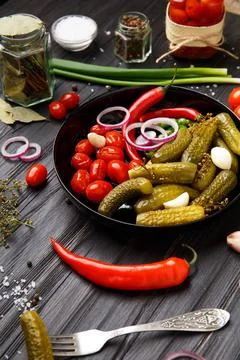 Assorted pickled vegetables in a black plate on a dark background. Foto stock