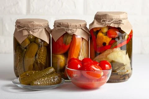 Assorted Pickled Vegetables in Glass Jars with Bowls of Pickles and Tomatoes Stock Photos