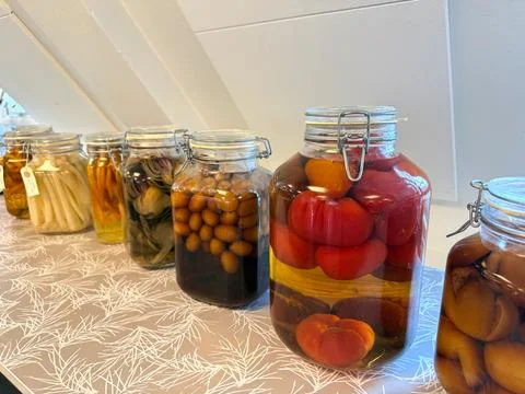 Assorted pickled vegetables in glass jars on shelf Stock Photos