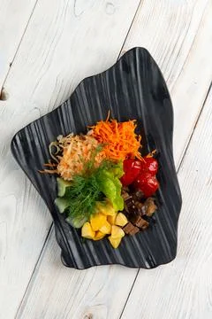 Assorted pickled vegetables in a plate on a light background. Stock Photos