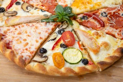 Assorted pieces of pizza closeup with different ingredients decorated with Basil Stock Photos