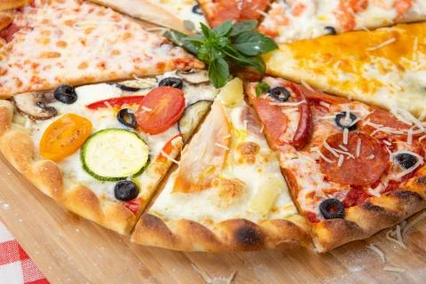 Assorted pieces of pizza closeup with different ingredients decorated with Basil Stock Photos