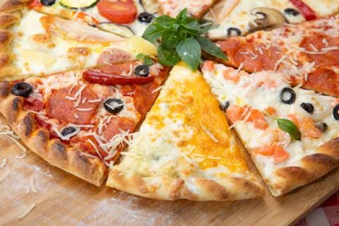 Assorted pieces of pizza closeup with different ingredients decorated with Basil Stock Photos