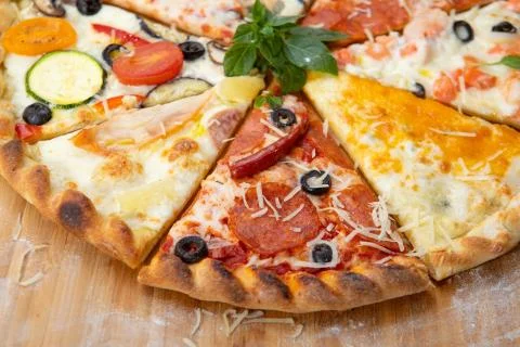 Assorted pieces of pizza closeup with different ingredients decorated with Basil Stock Photos